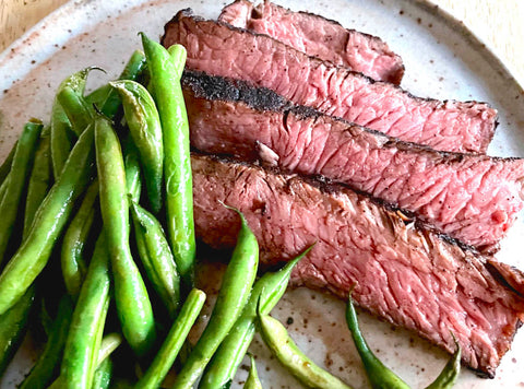 An overhead shot of a NY strip steak rubbed with Peet's Major Coffee Rub and grilled to perfection, along with a side of steamed green beans